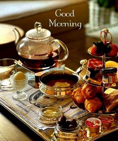 a tray filled with different types of food on top of a wooden table next to cups and saucers