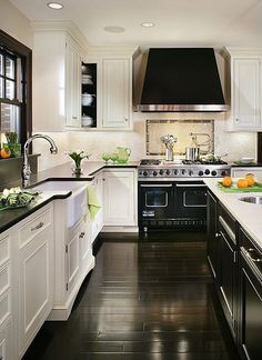 a kitchen with white cabinets, black counters and stainless steel stove top oven in the center