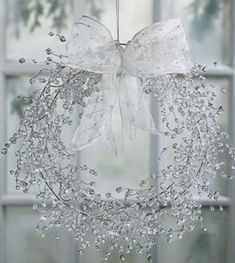 a white wreath hanging from the ceiling in front of a window with a bow on it