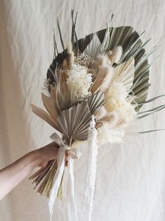 a person holding a bouquet of flowers on a white sheeted surface with their hands