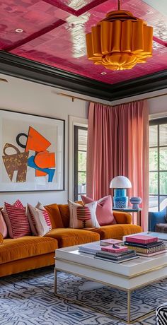 a living room with orange couches and paintings on the wall above them, along with pink curtains