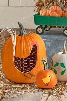 three pumpkins with designs on them sitting in hay next to a green carton