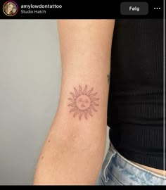 a woman's arm with a small sun tattoo on the left side of her arm