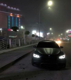 a black car driving down a street at night