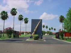 a large baseball bat sitting in the middle of a road with palm trees behind it