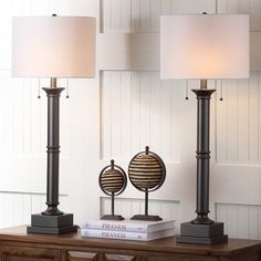 two lamps sitting on top of a wooden table next to a lamp shade and book