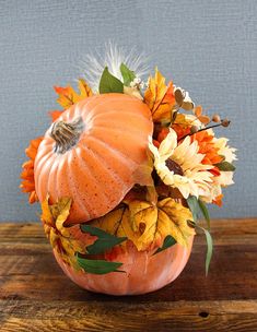 an orange pumpkin decorated with flowers and feathers