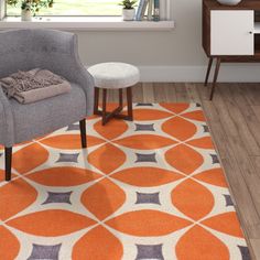 an orange and gray area rug in a living room with a grey chair, white table and window