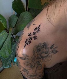 a woman with a flower tattoo on her back and shoulder is looking at the camera