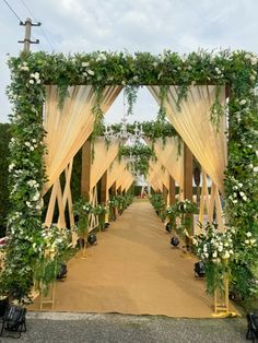 an outdoor wedding ceremony with white flowers and greenery on the aisle, surrounded by yellow drapes