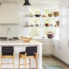 a kitchen with white cabinets and black chairs