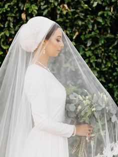 a woman wearing a veil and holding flowers