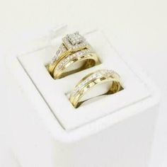 two wedding rings sitting on top of each other in a white display box with gold and diamonds