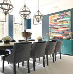 a dining room with blue walls and chandelier hanging from the ceiling, along with gray upholstered chairs