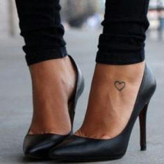 a woman's foot with a small heart tattoo on her left ankle and black jeans