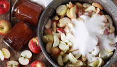 apples and sugar in a pan on a wooden table next to jars of apple cider