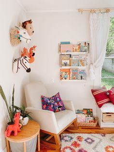 a white chair sitting in a living room next to a wooden table with books on it