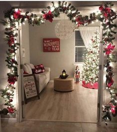 a living room decorated for christmas with red and white decorations on the walls, wreaths and lights hanging from the ceiling