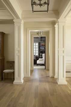 an empty hallway with wooden floors and white columns on either side of the hall door