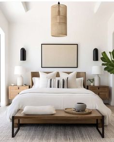 a bed with white sheets and pillows in a room