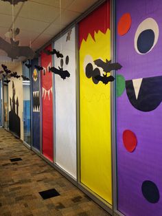 an office hallway decorated with brightly colored paper cut outs and monster faces on the doors