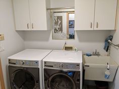 a washer and dryer in a small laundry room with white cupboards on the wall