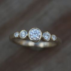 a three stone diamond ring sitting on top of a wooden table