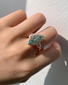 a woman's hand with a blue diamond ring on it