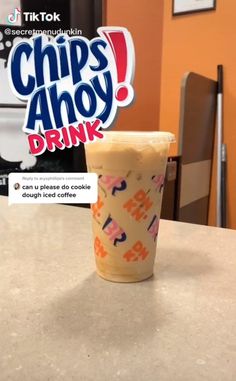 a plastic cup sitting on top of a counter next to a sign that says chips ahoy drink