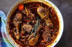 a pot filled with meat and vegetables on top of a table next to a towel