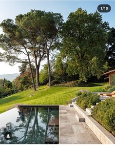 an outdoor swimming pool surrounded by greenery and trees in the background is a house