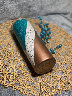 a blue and gold vase sitting on top of a doily next to some beads