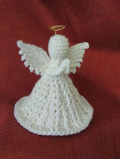 a white crocheted angel ornament sitting on top of a red blanket