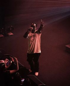 a man standing on top of a stage with his hand up in front of him