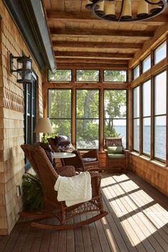 a porch with rocking chairs and windows on the side of it, overlooking lake champal