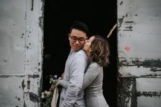 a man and woman kissing each other in front of an old building with peeling paint