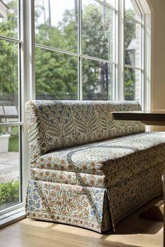 a couch sitting in front of a window next to a table