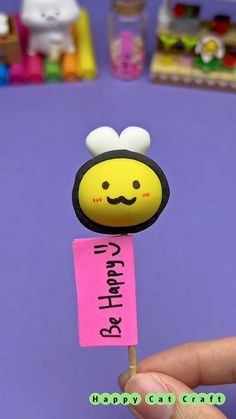 a person holding up a small stick with a smiley face on it's head