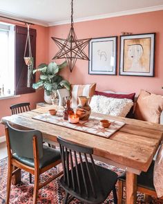 a dining room table with chairs and pictures on the wall above it, in front of a window