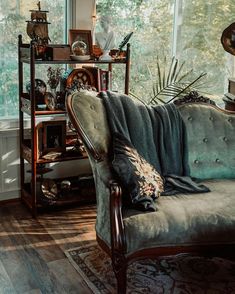 a couch sitting in front of a window next to a shelf filled with books and other items