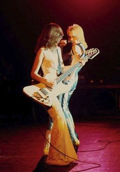 two female guitarists performing on stage at a concert