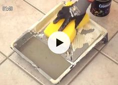 a person in black gloves and rubber gloves cleaning a tile floor with a yellow sponge