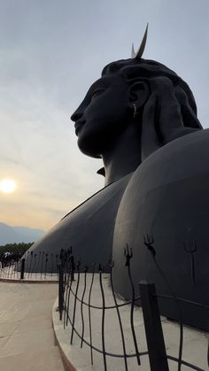 the sun is setting behind a large statue with horns on it's head and eyes