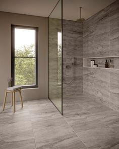 a bathroom with a walk in shower next to a large window and tiled flooring