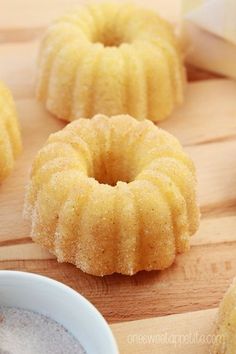 several donuts on a wooden cutting board with powdered sugar