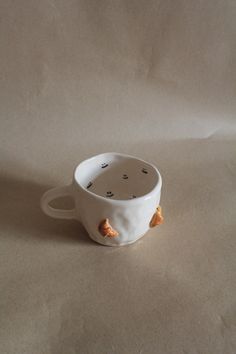 a white cup with orange croutons in it on a plain surface, ready to be used as a saucer