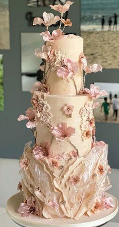 a three tiered wedding cake with pink flowers on the top and bottom, sitting on a white plate