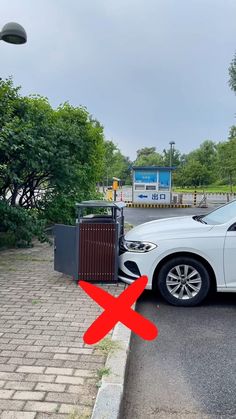 a white car parked in front of a gate with a red check mark on it