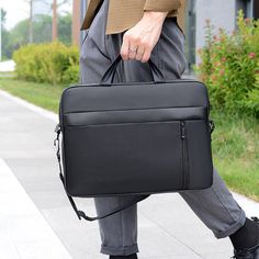 a man carrying a black briefcase down the street with his foot on the ground in front of him