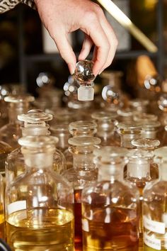 a person is picking up an item from a table full of glass bottles filled with liquid